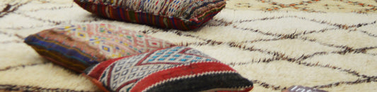 
Colorful patterned cushions on a cream rug with dark geometric lines.