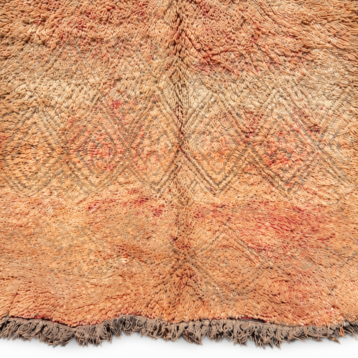 Detailausschnitt des beigen Vintage-Teppichs mit verblasstem Rautenmuster und pfirsichfarbenen Akzenten.