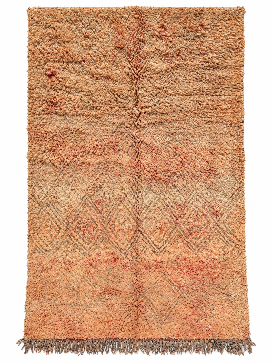 Beige vintage Moroccan rug with peach accents, a faded diamond pattern, and dark fringe on a white background.